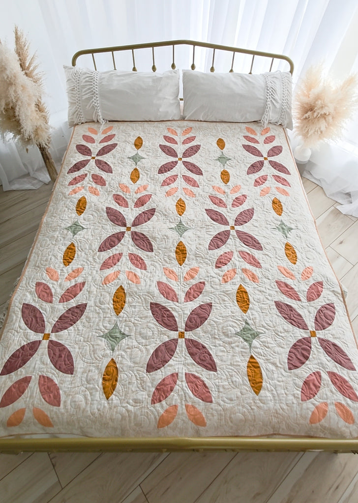 Quilt with leaf pattern on a bed in a bedroom setting | Flora Fields quilt kit