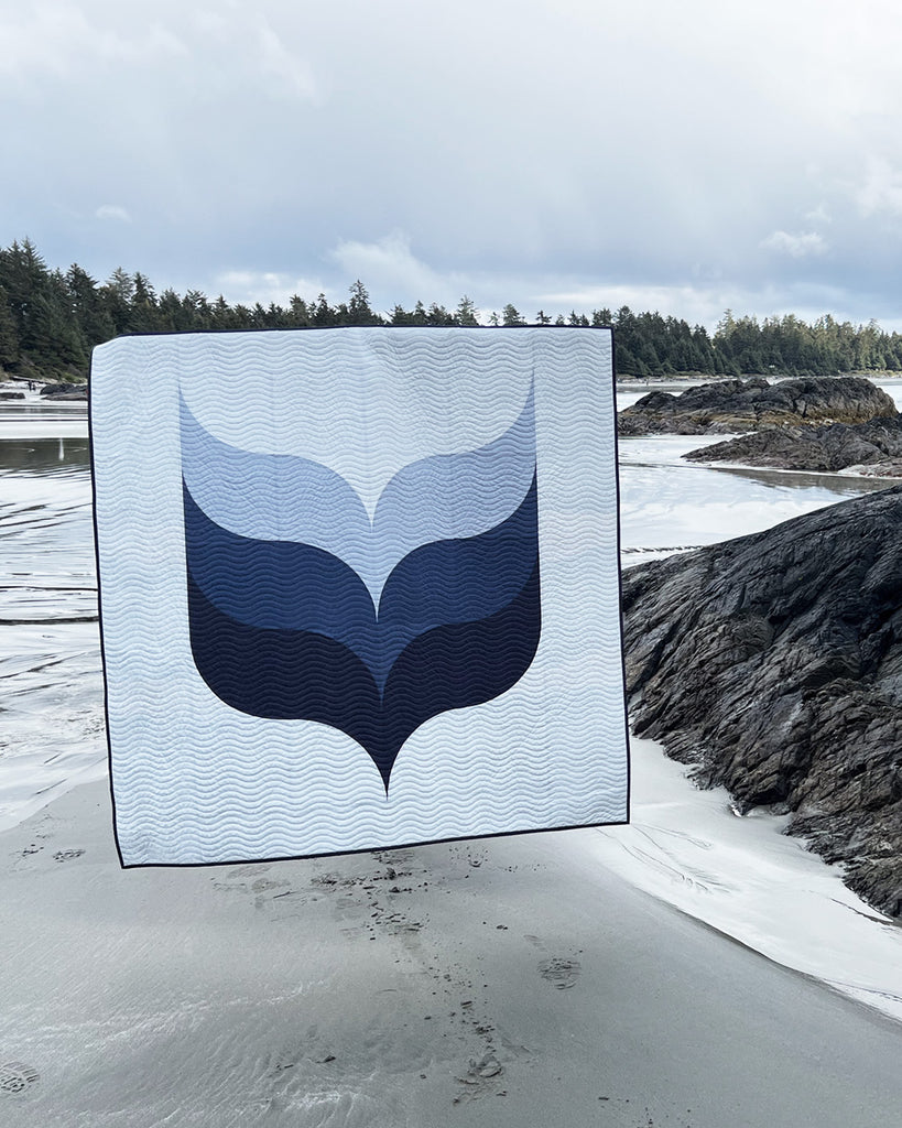 Quilt with a whale design displayed outdoors on a beach | Whale's Tail Quilt Kit